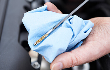 Checking oil dipstick with blue cloth